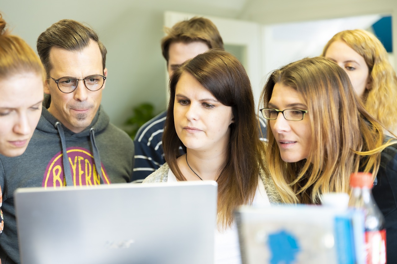 Team of People Huddled Around Laptop