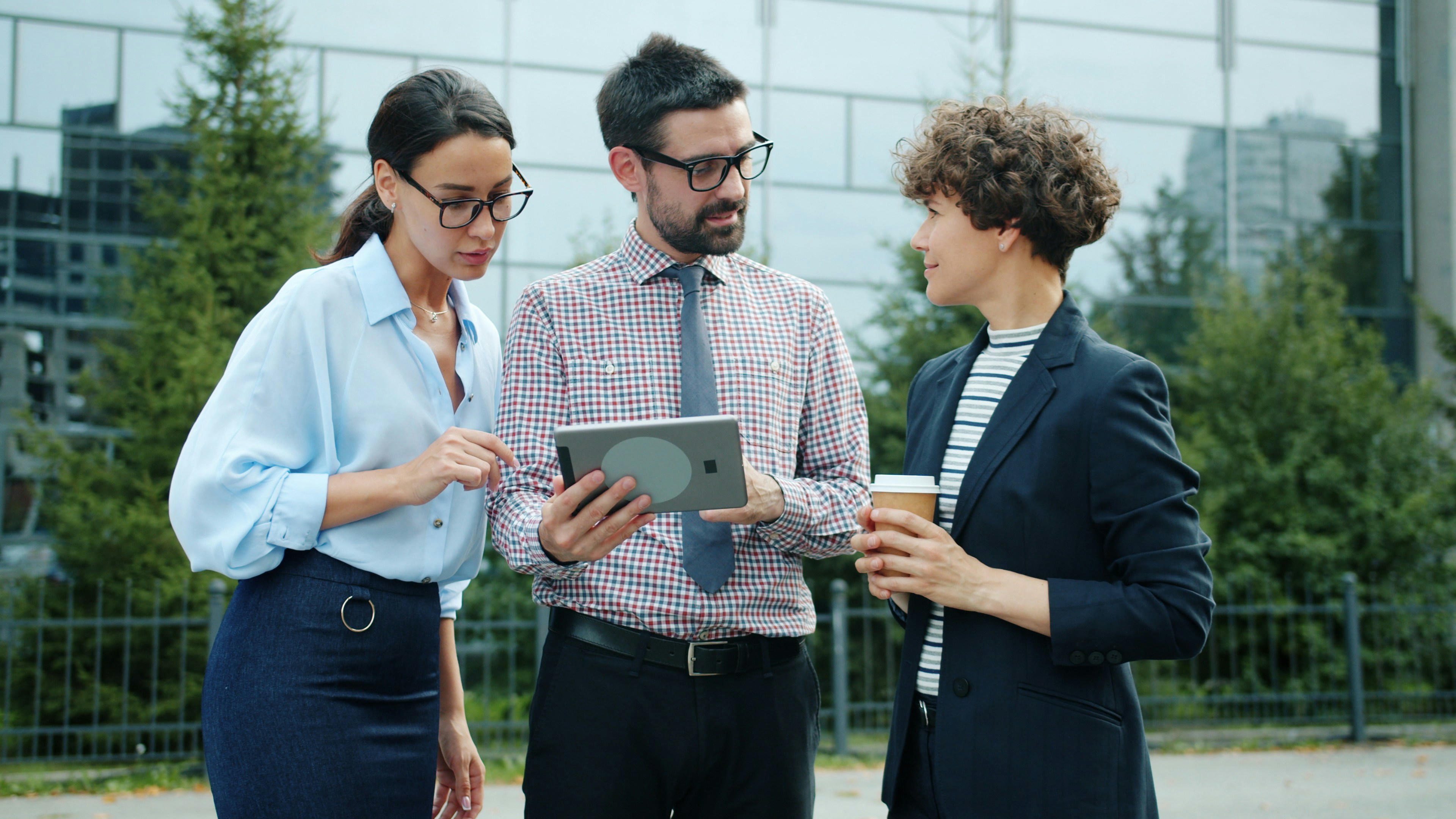 Three business people looking at tablet representing discussion over directors personal guarantees